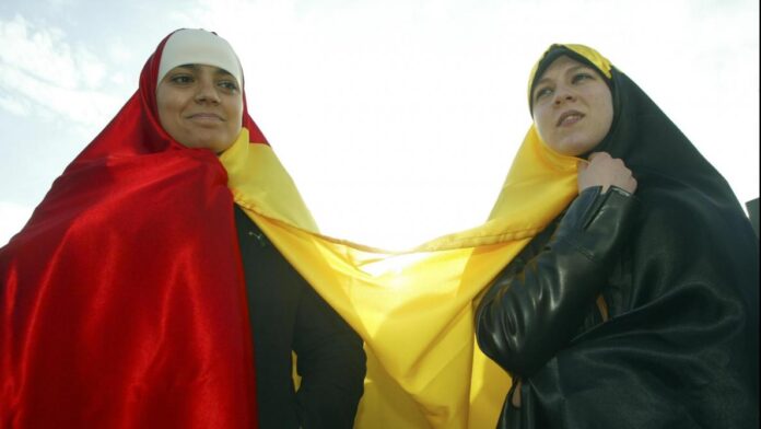 Deux femmes voilées drapées du drapeau belge